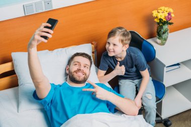 father and son taking selfie at ward clipart