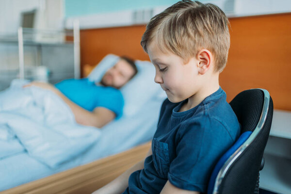 son sitting near sick father at ward