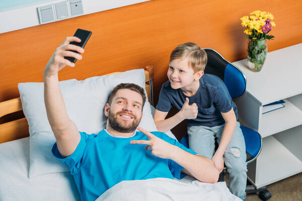 father and son taking selfie at ward