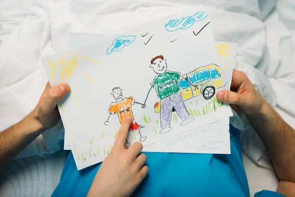 Son showing sick father drawings — Stock Photo, Image