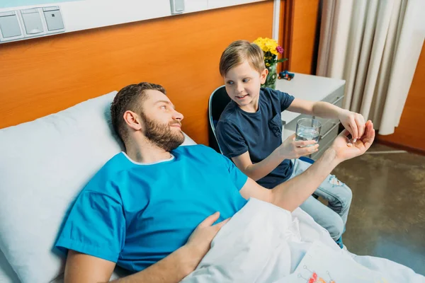Son giving pills to sick father — Stock Photo, Image