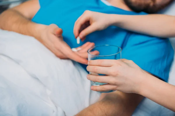 Filho dando pílulas para o pai doente — Fotografia de Stock