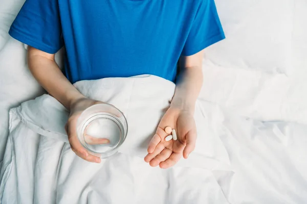 Menino com copo de água e medicamentos — Fotografia de Stock