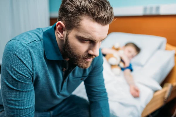 Vader in de buurt van zoon in ziekenhuisbed — Stockfoto