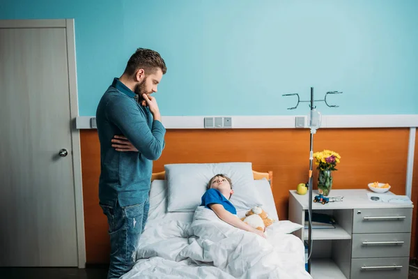 Pai perto filho na cama do hospital — Fotografia de Stock