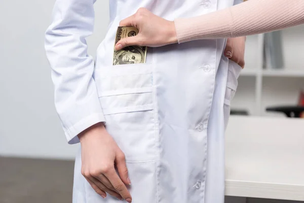 Patient mettre de l'argent dans la poche du médecin — Photo