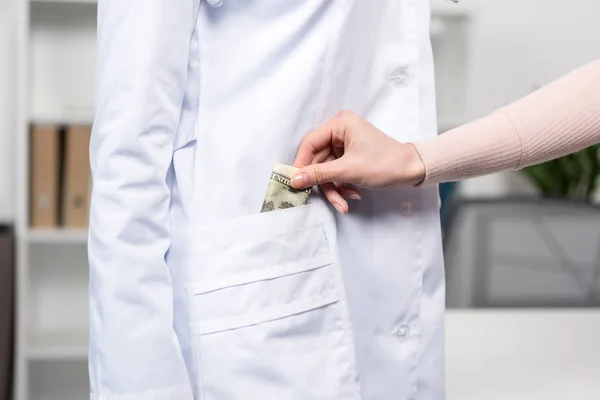 Patient putting money into doctor's pocket — Stock Photo, Image