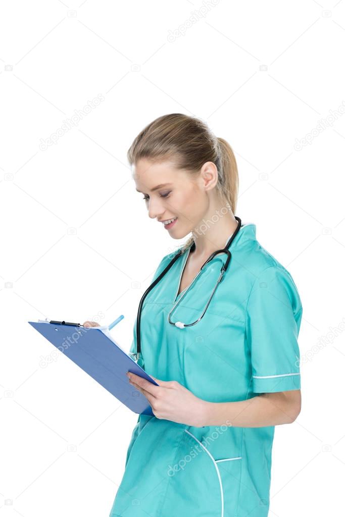 young nurse writing at clipboard