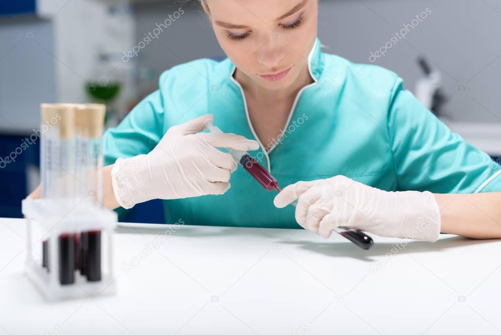 Nurse pouring blood samples into tubes