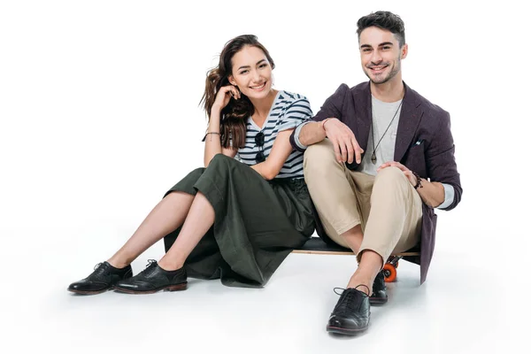 Smiling couple sitting on skateboard — Stock Photo, Image