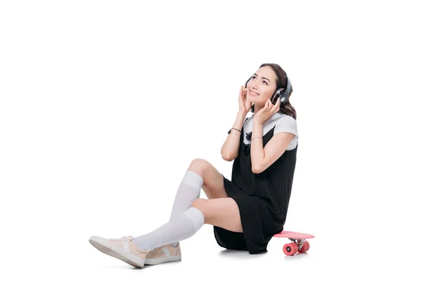 Woman listening music while sitting on skateboard — Stock Photo, Image