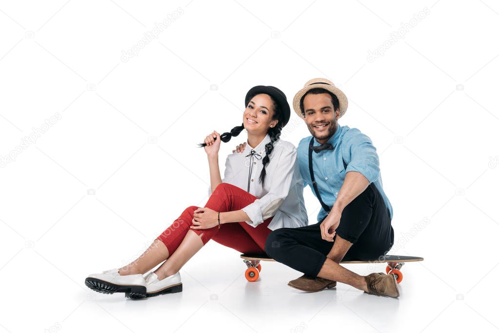 african american couple sitting on skateboard