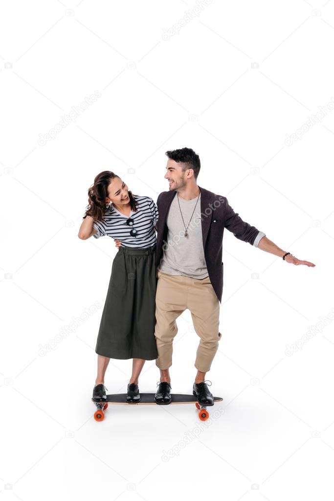 young cheerful couple riding on skateboard