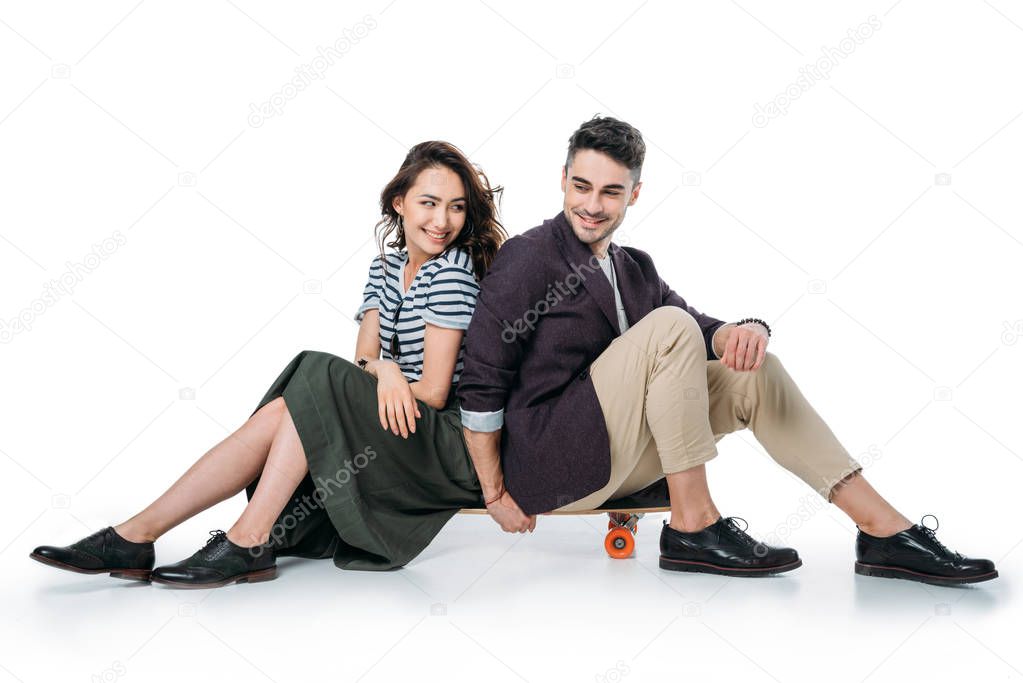 young smiling couple sitting on skateboard