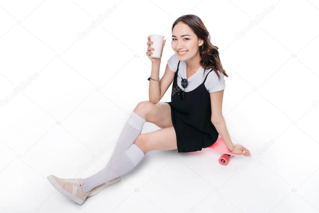 smiling asian girl sitting on skateboard