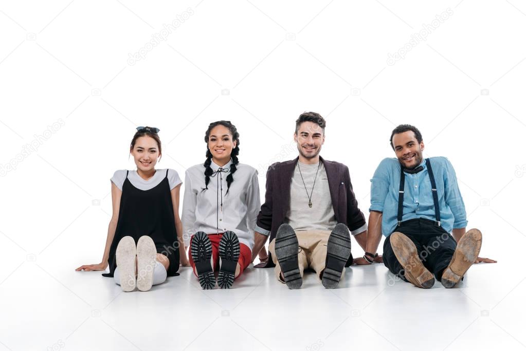 smiling multiethnic friends sitting on floor