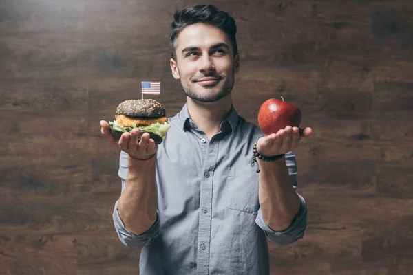 Hombre con hamburguesa y manzana — Foto de Stock