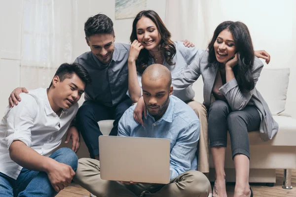 Amigos multiétnicos mirando a la computadora portátil en casa — Foto de Stock