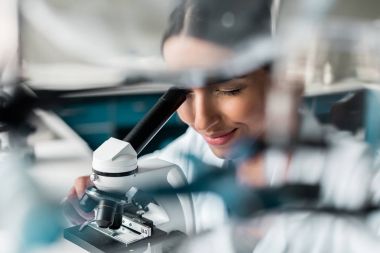 Scientist with microscope in lab