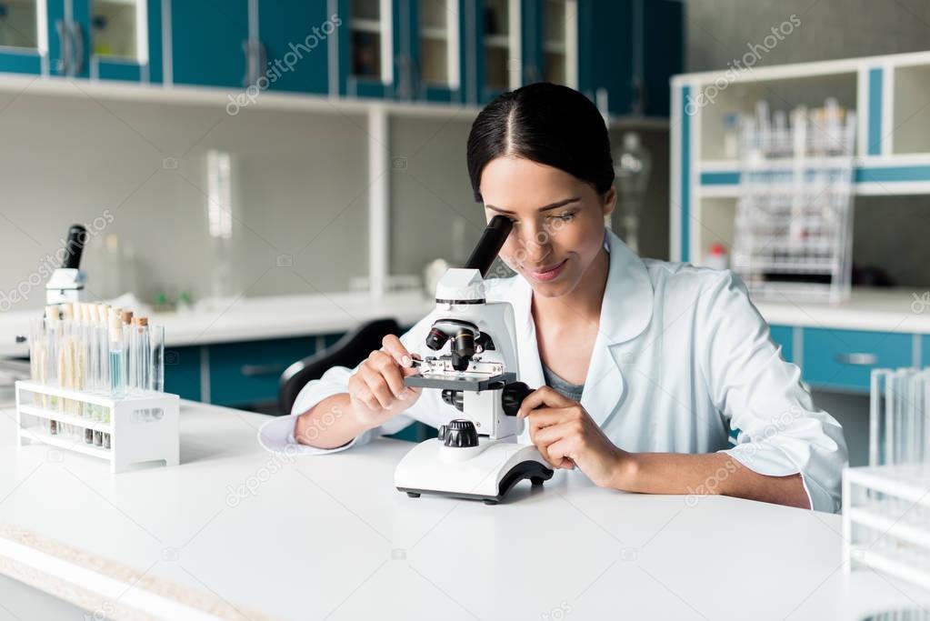 Scientist with microscope in lab