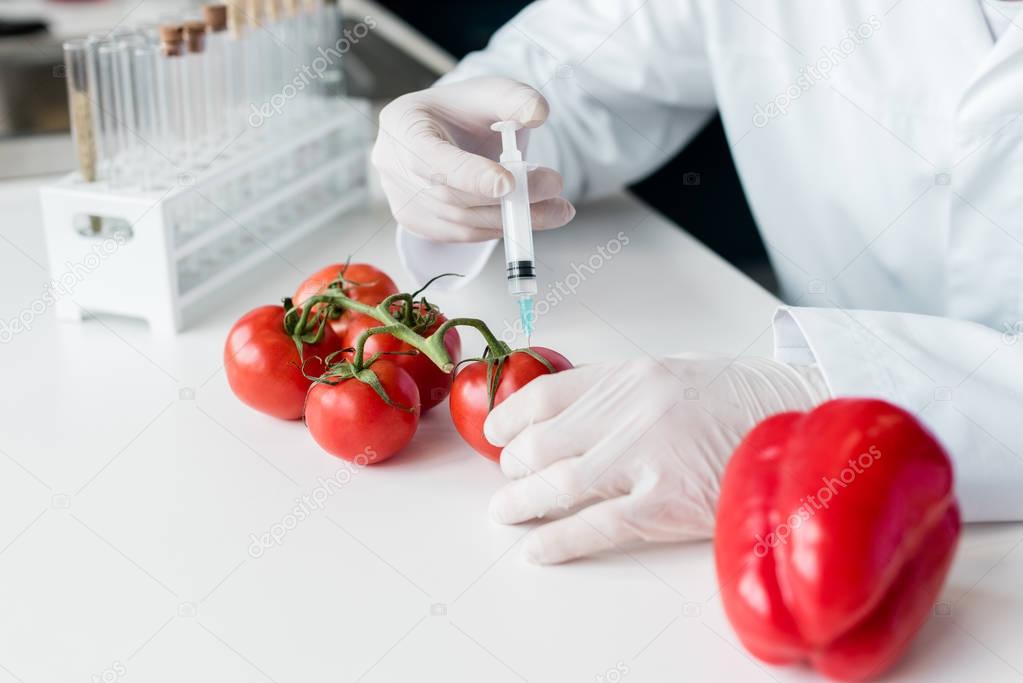 Scientist with syringe and tomatoes