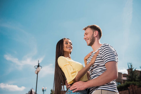 multiethnic couple hugging in city