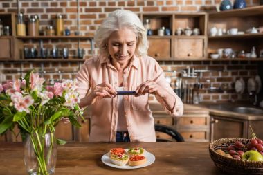 woman photographing plate with food at kitchen clipart