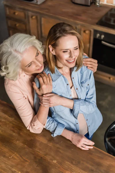 Dos mujeres abrazándose en la cocina — Foto de Stock