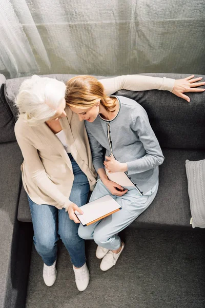 Gravid kvinna med mor på soffa — Stockfoto