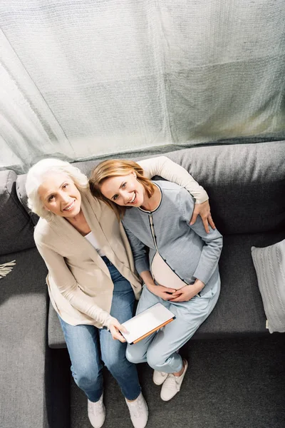 Беременная женщина с матерью на диване — стоковое фото