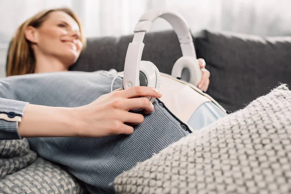 Pregnant woman with headphones on her belly — Stock Photo, Image