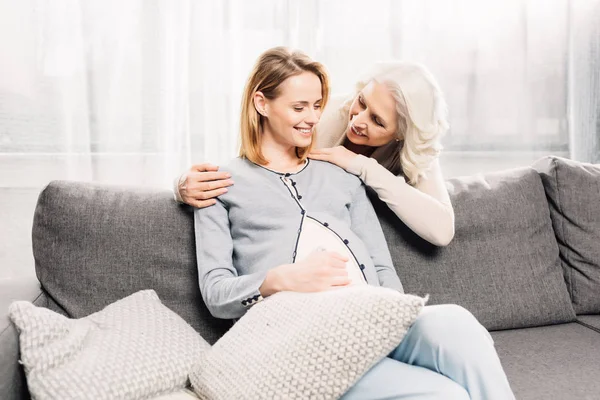 Gravid kvinna med mor på soffa — Stockfoto