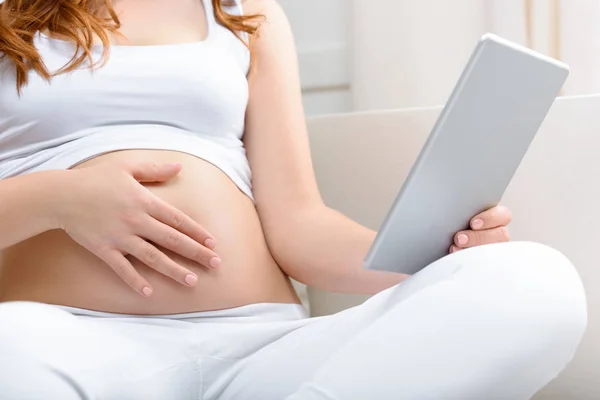 Těhotná žena s digitálním tabletu — Stock fotografie