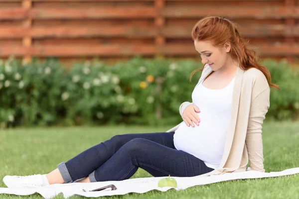 Terhes nő ül a gyep — Stock Fotó