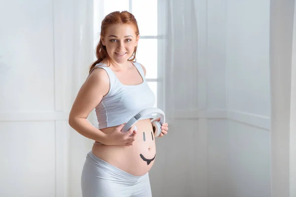 Mulher grávida com fones de ouvido na barriga — Fotografia de Stock