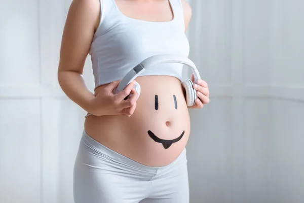 Pregnant woman with headphones on belly — Stock Photo, Image