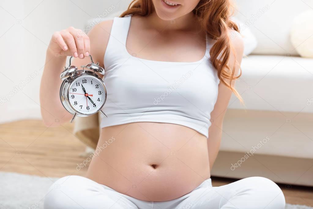 pregnant woman holding alarm clock 