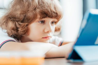 düşünceli kıvırcık çocuk tablet kullanma
