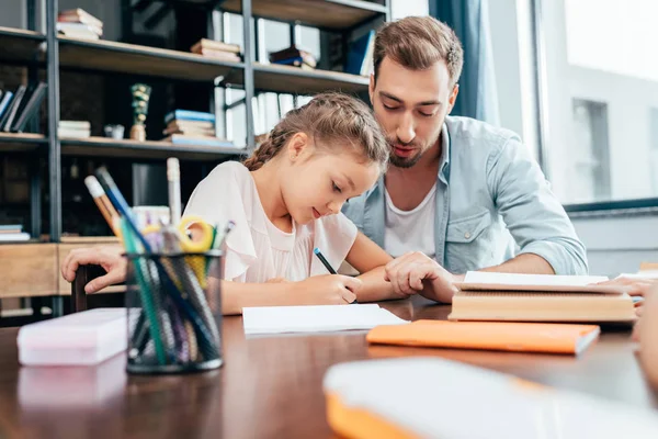 Padre haciendo la tarea con su hija — Foto de Stock