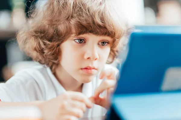 Thoughtful curly kid using tablet — Stock Photo, Image