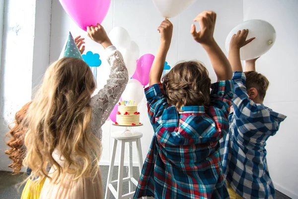 Kids reaching to birthday cake — Stock Photo, Image