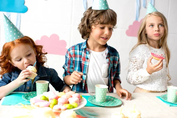 誕生日のテーブルにお菓子を食べる子供たち — ストック写真