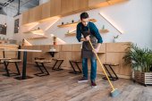 Arbeiter putzt Fußboden mit Kehrmaschine