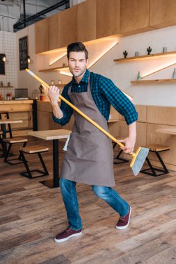 man having fun with broom in cafe clipart