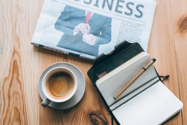 cup of coffee, newspaper and notebook on table clipart