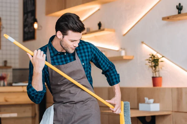 Man having fun with broom in cafe — Stock Photo, Image