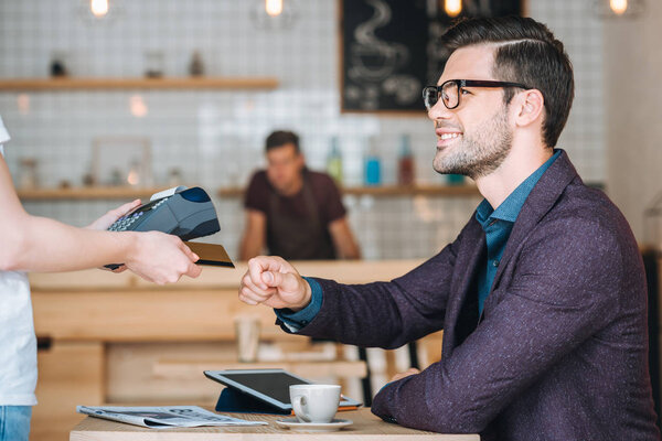 businessman paying with credit card in cafe