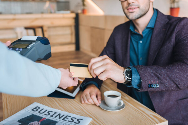 businessman paying with credit card in cafe