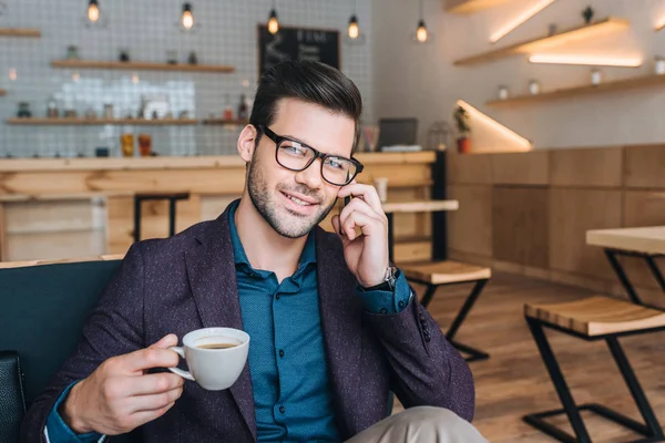 Homem de negócios com xícara de café falando no smartphone — Fotografia de Stock