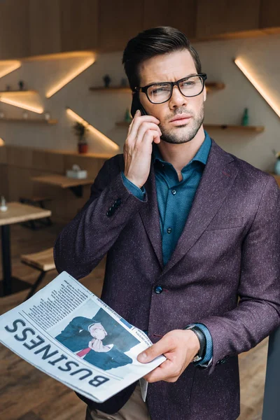 Uomo d'affari con giornale che parla su smartphone — Foto Stock